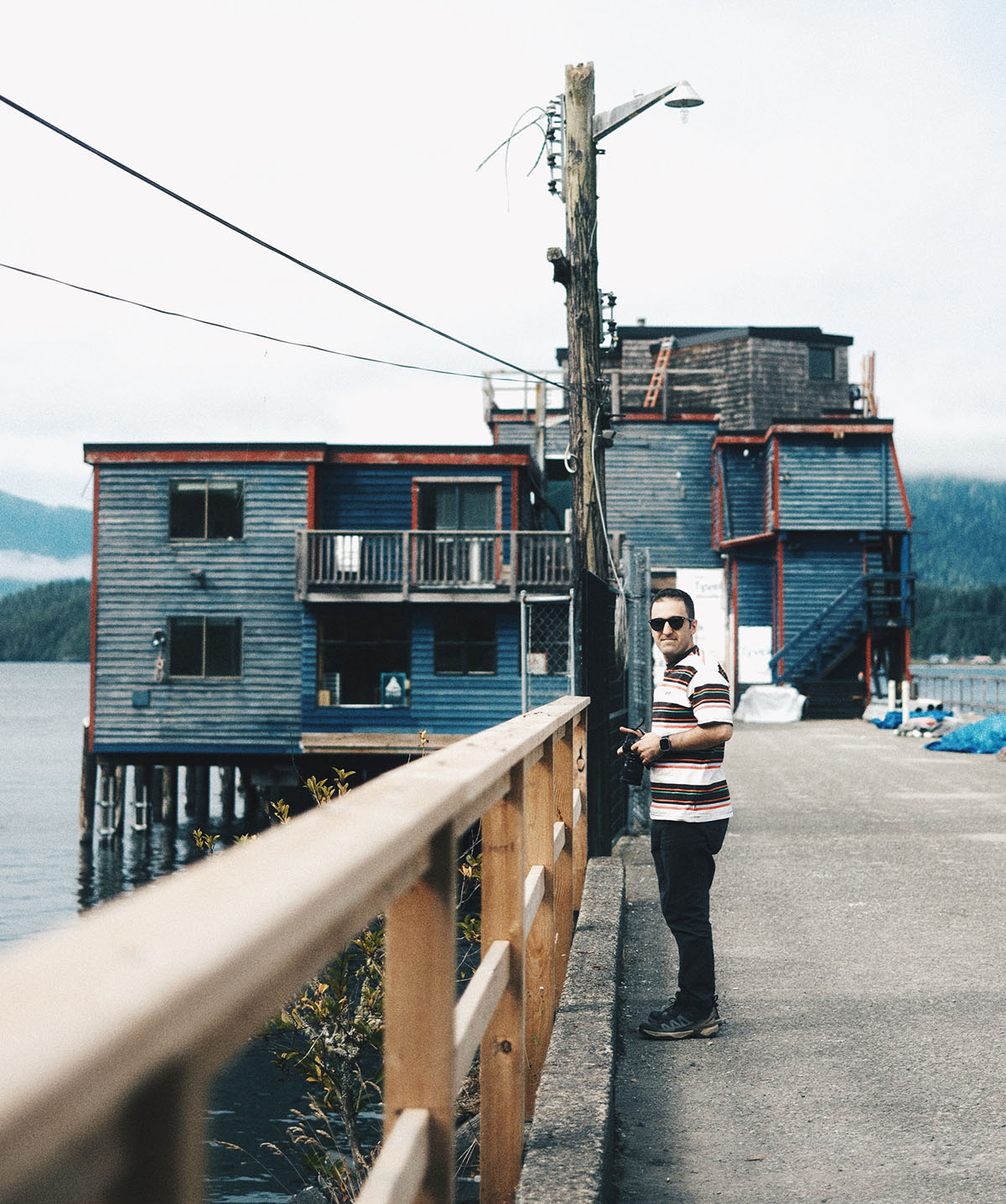 Portrait of Amir standing near the water with wooden buildings in the background